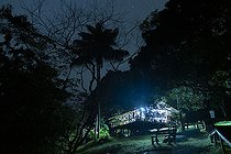 Biosphoto | 2583240 | Camp pararé, scientific station in the Nouragues nature reserve. Night falls quickly in the tropics, and some people work late in the carbet kitchen, which doubles as an office in the middle of the forest - Régina, French Guiana | &copy; Vincent Premel / Biosphoto