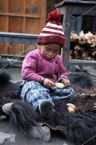 Biosphoto | 1073030 | Child peeling a potato on the skin of Yack Chame Nepal | &copy; Antoine Boureau / Biosphoto
