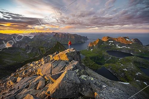 Biosphoto | 2464041 | Hiker stands at the summit, sunset with dramatic clouds, view from the top of Hermannsdalstinden, fjords, lakes and mountains, Moskenesøya, Lofoten, Nordland, Norway, Europe | &copy; Moritz Wolf / imageBROKER / Biosphoto