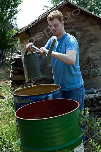 Biosphoto | 891626 | Jeune homme remplissant un arrosoir au potager | &copy; Philippe Giraud / Biosphoto
