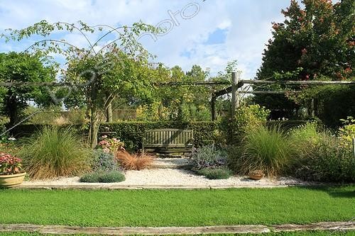 Biosphoto | 754146 | Pergola et banc dans le Jardin de Marie-Ange à Croisette ; Derrière la haie : Rudbeckie 'Herbstsonne' (fleurs jaunes) ; de chaque côté au pied des poteaux : Laîche d'automne, Carex rouge-brun 'Bronze Form', Népétas, Hortensia, Rosier grimpant et Oeillets | &copy; Hervé Lenain / Biosphoto