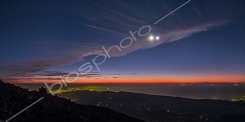 Biosphoto | 2624477 | Rare cirrus clouds on Venus and the lunar crescent in conjunction. The lights of San Cristobal de la Laguna and Santa Cruz outline the contour of the caldera below, while offshore to the right, the island of Gran Canaria breaks the twilight line. Mount Teide, Canary Islands, Spain. | &copy; Philippe Jacquot / Biosphoto