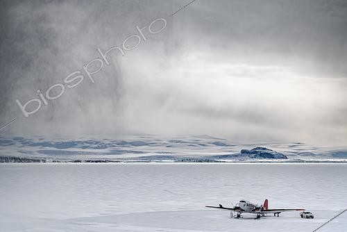 Biosphoto | 2590466 | The Basler, stationed on the Terra Nova Bay ice floe in front of the Mario Zucchelli base. The mechanics take advantage of a rare lull to carry out routine maintenance. The aircraft is strapped to the ground. A squall arrives from the left. Victoria Land, Antarctica | &copy; Armand Patoir / Biosphoto