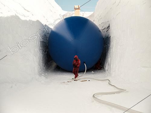 Biosphoto | 2592800 | Two technicians install and inflate a cylindrical balloon 5 meters in diameter and 35 meters long. The balloon serves as a mold for the snow to be deposited on top. Once deflated, the result is a cellar spacious enough to store vehicles and other equipment. The beige and orange structure at the far end is the fire escape. Concordia Antarctic Research Station, Dome C plateau, East Antarctica. | &copy; Armand Patoir / Biosphoto